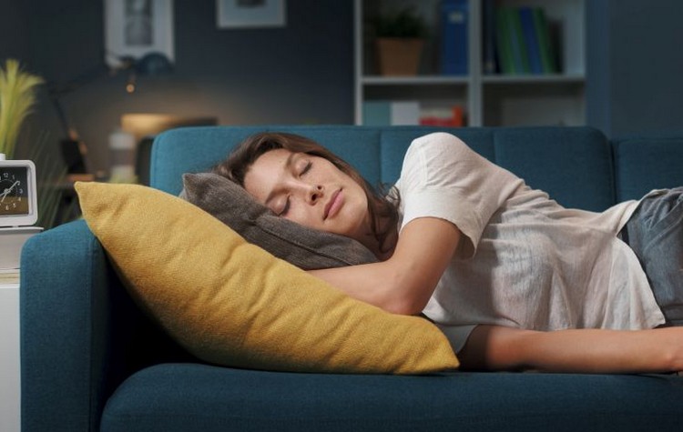 Young relaxed woman lying down on the sofa at home and sleeping